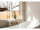 Close-up of a modern bathtub with bronze hardware and bright natural light from the window at 4565 Elm Ct, Denver, CO 80211