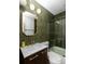 Modern bathroom featuring sleek green tiling, glass shower door, and vanity with gold fixtures at 4565 Elm Ct, Denver, CO 80211