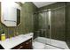 Modern bathroom boasting sleek green tiling, glass shower door, and vanity with gold fixtures at 4565 Elm Ct, Denver, CO 80211