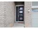 Stylish black front door with glass panels, complemented by light brick and a welcoming mat at 9130 Fraser River, Littleton, CO 80125