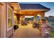 Large covered patio with brick accents, outdoor seating, and views of the surrounding neighborhood at 6963 S Espana Way, Centennial, CO 80016