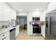 Bright kitchen with white cabinets, stainless appliances, and light wood flooring at 5541 E 65Th Ave, Commerce City, CO 80022