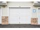 Closed white garage door featuring stone facade and an exterior light fixture at 19019 E Warren Dr # H104, Aurora, CO 80013