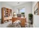 Well-lit home office featuring wood desk, bookcase, decor, and a sunny window view at 19019 E Warren Dr # H104, Aurora, CO 80013