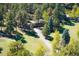 Aerial view of a charming home nestled among lush trees and expansive green lawns with a winding driveway at 28454 Meadow Dr, Evergreen, CO 80439