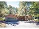 Exterior view of a home with garage and wood accents, surrounded by lush trees and a paved driveway at 28454 Meadow Dr, Evergreen, CO 80439