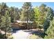Exterior view of a charming home with wood details, surrounded by lush greenery and towering pine trees at 28454 Meadow Dr, Evergreen, CO 80439