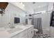 Bright bathroom featuring a double sink vanity, framed mirror, and a shower-tub combo with a gray shower curtain at 131 S Vandriver Way, Aurora, CO 80018