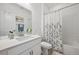 Well-lit bathroom with a single sink vanity, framed mirror, and a shower-tub combo with a floral shower curtain at 131 S Vandriver Way, Aurora, CO 80018