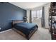 Contemporary bedroom with blue accent wall, a queen-size bed, neutral carpet, and a large window with curtains at 131 S Vandriver Way, Aurora, CO 80018