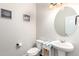 Elegant powder room featuring pedestal sink, oval mirror and framed art prints at 2881 Black Canyon Way, Castle Rock, CO 80109