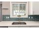 Kitchen with stainless steel sink, white quartz counters and blue glass subway tile backsplash at 2881 Black Canyon Way, Castle Rock, CO 80109