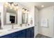 Modern bathroom with dual sinks, framed mirrors, updated lights and blue cabinetry at 2881 Black Canyon Way, Castle Rock, CO 80109