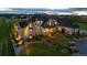 Dusk view of home featuring stone facade, manicured landscaping, and gated entry at 15355 Zuni St, Broomfield, CO 80023