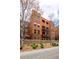 Contemporary brick condo building with balconies, landscaping, and a blue patio umbrella for outdoor relaxation at 1631 N Emerson St # 117, Denver, CO 80218