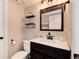 Bathroom with white countertops, dark vanity, framed mirror and decorative shelves at 9866 Spring Hill Ln, Highlands Ranch, CO 80129