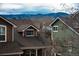 A view of two homes with stunning mountain views, roof details, and a mix of green and brown siding at 9866 Spring Hill Ln, Highlands Ranch, CO 80129