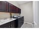 Well-equipped laundry room with dark cabinets, a white utility sink and modern washer and dryer at 3790 Mighty Oaks St, Castle Rock, CO 80104