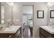 Well-lit bathroom featuring dual sink vanities, a large mirror, and a view into the bedroom at 3040 S Dexter Way, Denver, CO 80222