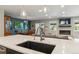 Modern kitchen featuring a large island with sink, pendant lighting, and open view to the living and dining areas at 3040 S Dexter Way, Denver, CO 80222