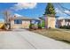 Charming front exterior with a well-manicured lawn and a long driveway leading to the home at 10699 W 9Th Pl, Lakewood, CO 80215