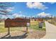 A wooden sign for Sunset Park is surrounded by a walkway and playground equipment under a blue sky at 10699 W 9Th Pl, Lakewood, CO 80215