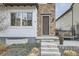 Close-up of the home's entrance featuring a stone facade, wood door, and landscaped front yard at 2640 S Orchard St, Lakewood, CO 80228