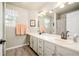 Bright bathroom with double sink vanity, framed mirror, and wood-look flooring at 1210 Snowberry Ln, Broomfield, CO 80020