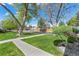 Landscaped front yard with mature trees and green lawn leading to homes and a wooden fence at 9901 E Evans Ave # 9A, Aurora, CO 80247