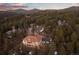 Areal view of home nestled in wooded area with sunset sky and mountain views at 21016 Horse Bit Way, Morrison, CO 80465