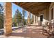 Spacious back porch supported by stacked stone columns with ample space for seating and relaxation at 21016 Horse Bit Way, Morrison, CO 80465