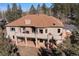Two-story house with a large balcony, brick supports, mature trees and a brown shingle roof at 21016 Horse Bit Way, Morrison, CO 80465