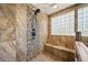 Close-up of a shower with decorative pebble accents, a built-in bench, and glass block window at 21016 Horse Bit Way, Morrison, CO 80465