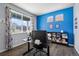 Well-lit office with natural light, blue accent wall, desk, and stylish shelving for a functional workspace at 2144 Rosette Ln, Castle Rock, CO 80104