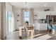 Dining room with a bright window, and modern light fixture, next to a white kitchen with an island at 4530 Cattle Cross Trl, Castle Rock, CO 80104