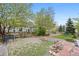Landscaped backyard with artificial grass, mature trees, and a gravel sitting area at 13250 Wild Basin Way, Broomfield, CO 80020