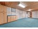 Finished basement featuring wood paneling, cabinets, and blue carpeting for a cozy and functional space at 11957 Claude Ct, Northglenn, CO 80233