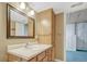 Bathroom vanity with an updated mirror, drawers, and lighting; and a doorway leading to the carpeted basement at 11957 Claude Ct, Northglenn, CO 80233
