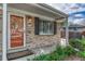 Inviting home entrance with a bright orange door, brick facade, and manicured landscaping at 11957 Claude Ct, Northglenn, CO 80233