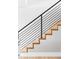 Modern staircase featuring sleek metal railings, hardwood steps, and white risers with natural light at 2048 Meade St, Denver, CO 80211
