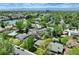 An aerial view of a suburban neighborhood nestled amongst mature green trees, buildings, and mountain views at 3245 S High St, Englewood, CO 80113