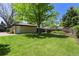 Large, well-maintained backyard with lush green lawn, mature tree, and detached garage at 3245 S High St, Englewood, CO 80113