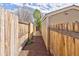 Narrow mulch-covered walkway between wooden fences leading to the backyard of this house at 2190 S Uravan St, Aurora, CO 80013