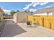 Concrete patio area in the backyard with a shed, yellow wooden fence, and outdoor seating with a fire pit at 2190 S Uravan St, Aurora, CO 80013
