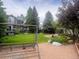 Backyard with lush green lawn, mature trees and landscaping features a swing, hot tub and pergola at 12742 Clermont St, Thornton, CO 80241