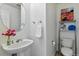 Well-lit powder room with a sink, toilet, mirror and decorative wall shelving adding charm to the space at 8645 Coors St, Arvada, CO 80005