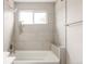 Bright bathroom with a soaking tub and shower, a large window and neutral tiling at 2134 S Galapago, Denver, CO 80223