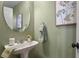 Elegant powder room with pedestal sink, decorative mirror, and soft, soothing color palette at 7651 E 26Th Ave, Denver, CO 80238