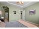Serene bedroom with neutral carpet, soft green walls, arched entryway, and a ceiling fan for added comfort at 7651 E 26Th Ave, Denver, CO 80238