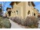 A view of a townhome with stucco exterior, arched windows, and landscaped walkway at 7651 E 26Th Ave, Denver, CO 80238